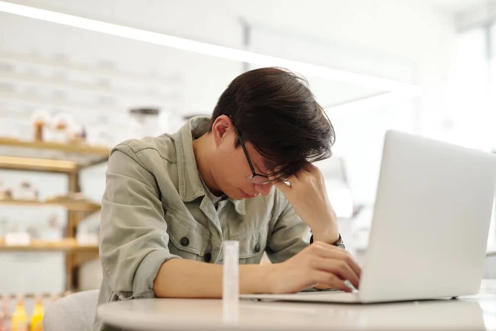 デスクワークの合間にパソコンの前で疲れた表情を見せる男性会社員